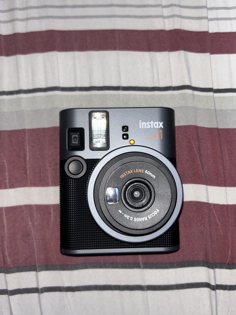 Fujifilm Instax Mini 41 Instant Camera (Category: Cameras) located in Manila. Submitted by 444vincci (Listing ID 1468487002, Image 3). Description: - Model: Fujifilm Instax Mini 41 Instant Camera - Color: Sleek Dark Grey with a textured grip handle - Lens: 60mm Instax lens (0.3m to infinity focus range) - Key Features: Built-in flash, close-up mode, and easy switch operation - Display: Rear film counter display - Power: Battery-operated - Conditi
