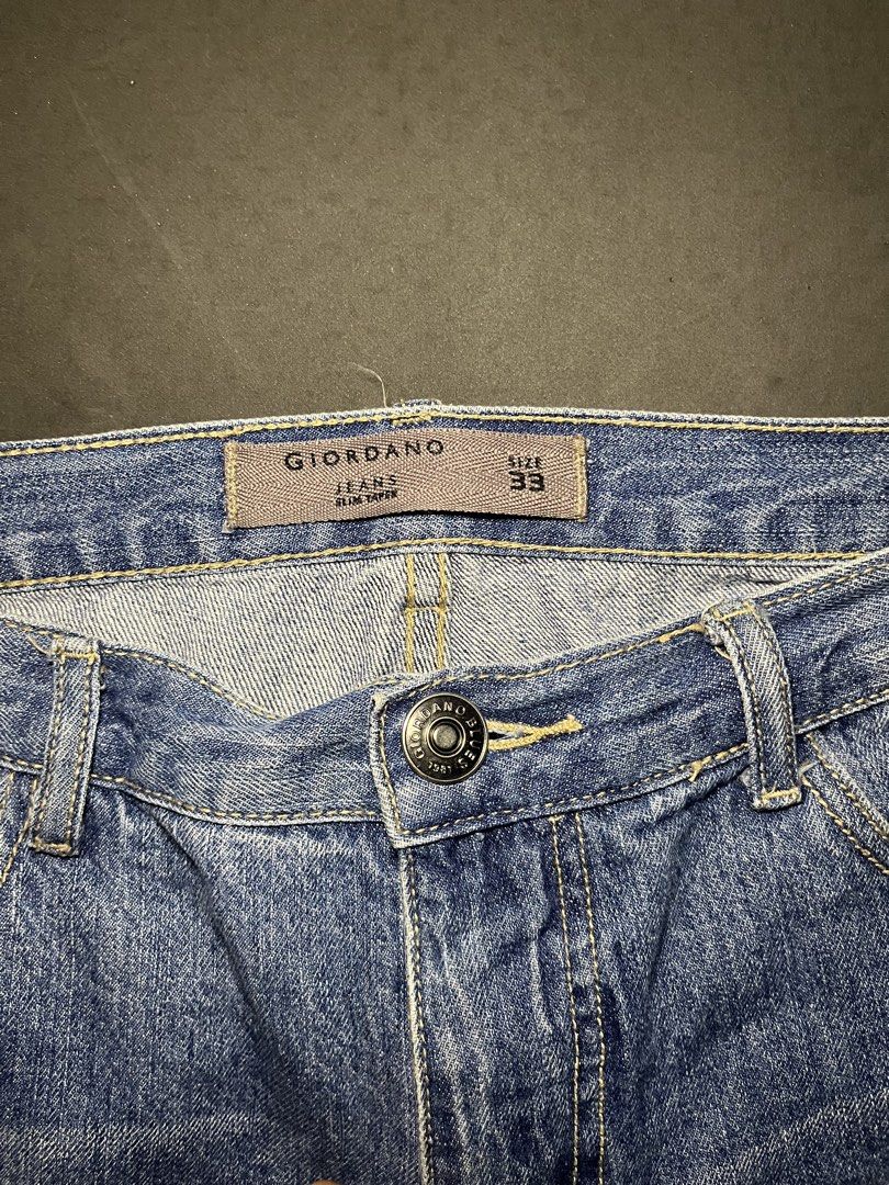 Giordano Blue Slim Taper Jeans Size 33 (Category: Jeans) located in Muntinlupa City. Submitted by pastforwardthrift (Listing ID 1468498974, Image 3). Description: - Brand: Giordano - Style: Slim taper jeans with slight distressing on thighs - Color: Classic blue wash - Size: 33 - Material: 99% cotton, 1% other fibres - Details: Branded button closure, zip fly, standard 5-pocket design, contrasting yellow stitching - Origin: Made in China.