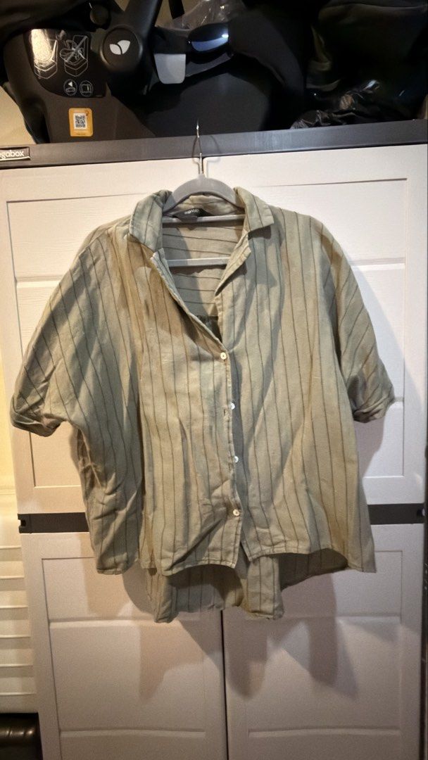 Green Striped Button-Down Short Sleeve Shirt (Category: Shirts) located in Manila. Submitted by adoptmypreloveditems (Listing ID 1468477062, Image 1). Description: - Color & Pattern: Green with thin dark stripes - Fit: Relaxed fit with short sleeves and collar neck - Details: Front button closure with white buttons, curved hem longer in the back - Material: Light and breezy fabric for all-day comfort - Style: Casual, highly versatile and easy to 