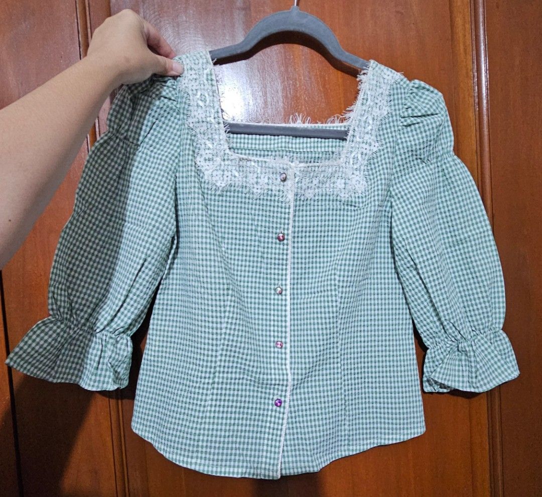 Green White Gingham Check Blouse with Lace Trim (Category: Blouses) located in Quezon City. Submitted by tiamaureia (Listing ID 1468390899, Image 1). Description: - Green and white gingham check blouse with square neckline. - Detailed with white lace trim along the collar and front placket. - Long sleeves with ruffled cuffs. - Buttons down the front with rhinestone embellishments. .