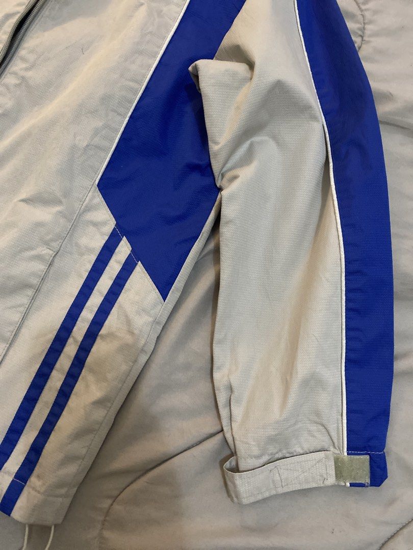 Grey and Blue Windbreaker Jacket with Stripe Details (Category: Coats, Jackets and Outerwear) located in Manila. Submitted by newkkmora98454 (Listing ID 1468316623, Image 3). Description: - Color: Grey with striking blue panel inserts - Closure: Full zip with high stand-up collar and snap button tab - Design: Dual vertical stripe graphics near the front hem - Fit: Adjustable hook-and-loop wrist cuffs and cinched drawcord hem - Material: Lightweig