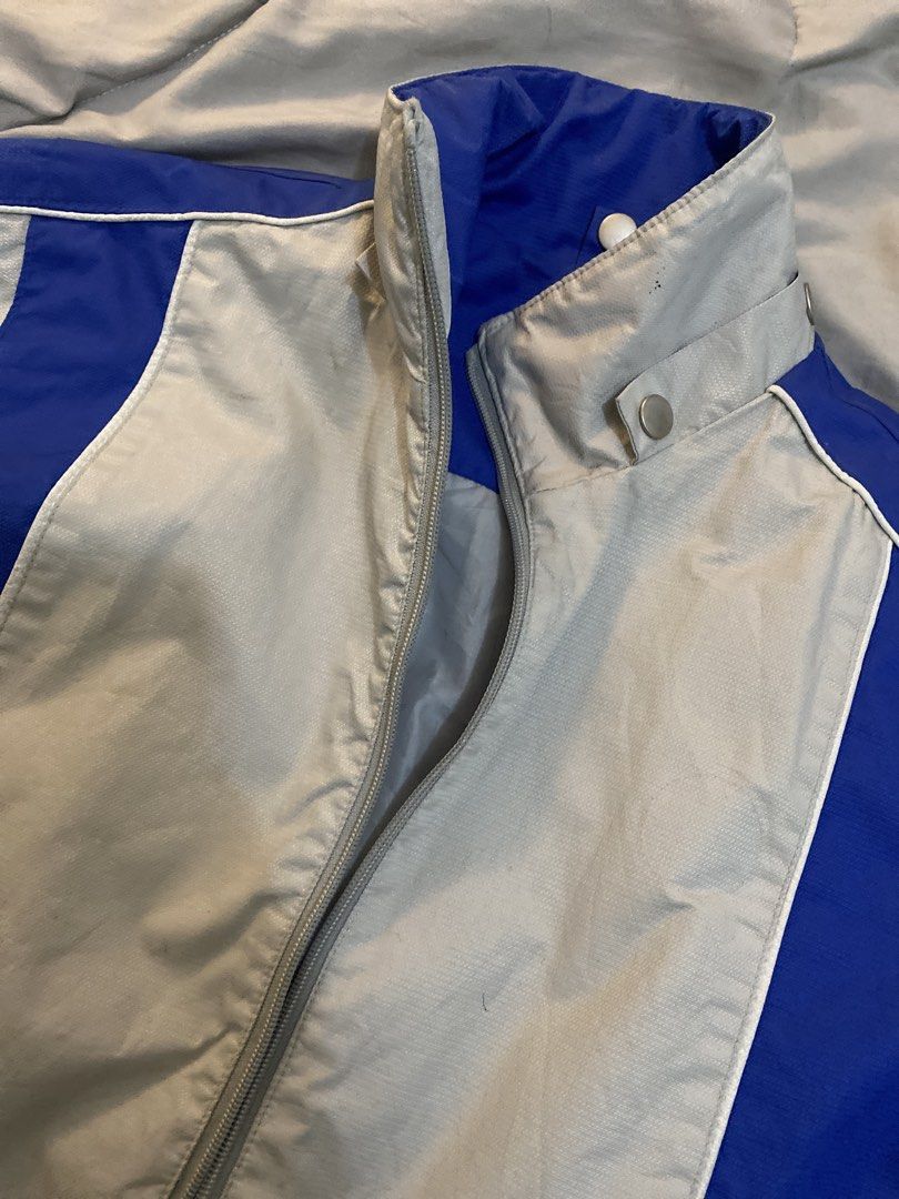 Grey and Blue Windbreaker Jacket with Stripe Details (Category: Coats, Jackets and Outerwear) located in Manila. Submitted by newkkmora98454 (Listing ID 1468316623, Image 2). Description: - Color: Grey with striking blue panel inserts - Closure: Full zip with high stand-up collar and snap button tab - Design: Dual vertical stripe graphics near the front hem - Fit: Adjustable hook-and-loop wrist cuffs and cinched drawcord hem - Material: Lightweig