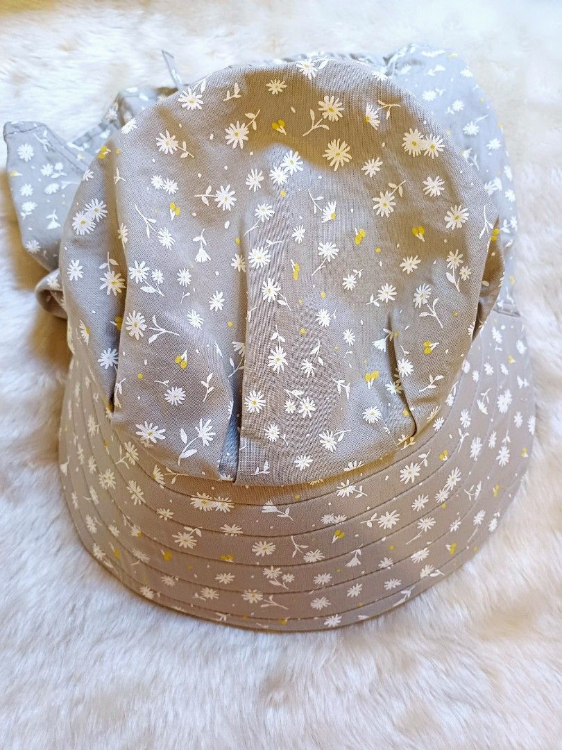Grey Floral Sun Hat With Neck Flap (Category: Hats & Beanies) located in Pasig City. Submitted by eden_online_shop (Listing ID 1468357954, Image 1). Description: - Color & Pattern: Grey with all-over small white flowers and yellow details - Sun Protection: Wide brim and long neck flap to block harmful rays - Easy Closure: Convenient front velcro closure for quick wear - Secure Fit: Ties underneath keep the hat safely in place - Condition: Like ne