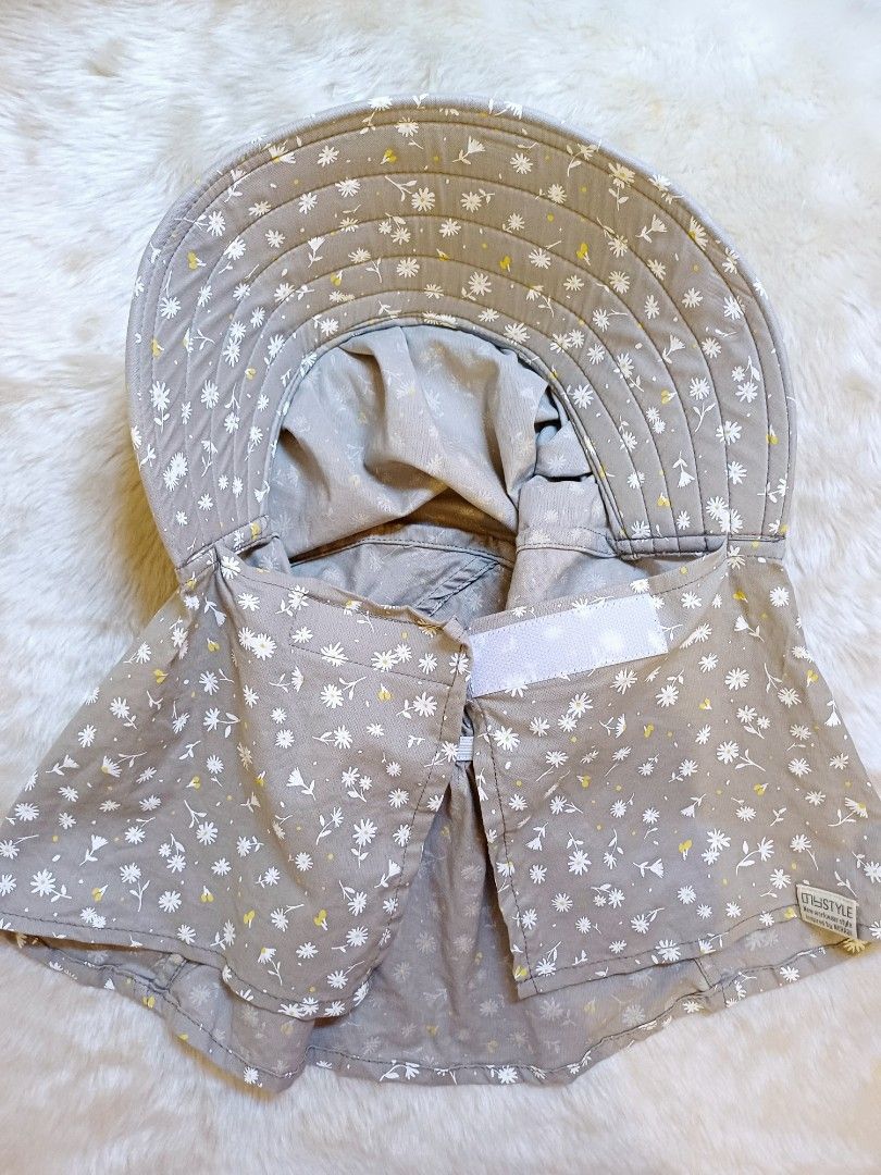 Grey Floral Sun Hat With Neck Flap (Category: Hats & Beanies) located in Pasig City. Submitted by eden_online_shop (Listing ID 1468357954, Image 2). Description: - Color & Pattern: Grey with all-over small white flowers and yellow details - Sun Protection: Wide brim and long neck flap to block harmful rays - Easy Closure: Convenient front velcro closure for quick wear - Secure Fit: Ties underneath keep the hat safely in place - Condition: Like ne