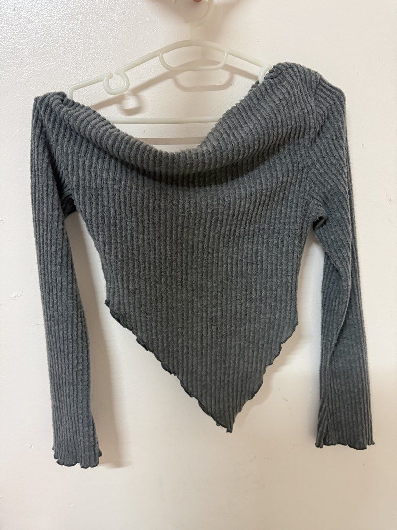 Grey Off-Shoulder Asymmetrical Long Sleeve Top (Category: Longsleeves) located in Manila. Submitted by unclutterwme (Listing ID 1468425749, Image 1). Description: Grey long sleeve top with an off-shoulder neckline. Ribbed textured fabric throughout. Asymmetrical pointed hemline hanging down the center. Lettuce trim details on the cuffs and bottom edge. Easy to pair with high-waisted jeans or skirts. Soft and stretchy material..