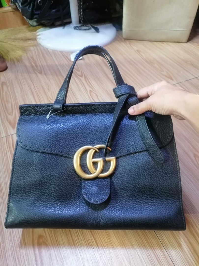 Gucci Black Leather Handbag (Category: Luxury Bags & Wallets) located in Digos. Submitted by crodualady82694 (Listing ID 1468283665, Image 1). Description: - Brand: Gucci - Material: Premium black grained leather - Hardware: Gold-tone interlocking G front clasp - Closure: Secure zippered top opening - Features: Structured silhouette, sturdy top handles, and rings for a shoulder strap (strap not included) - Interior: Clean lining with official Guc