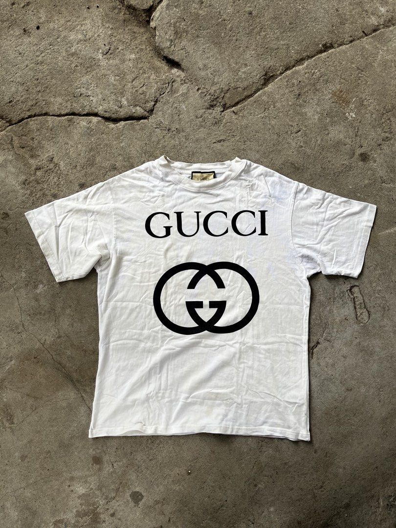 Gucci Interlocking G Logo White T-Shirt (Category: Shirts) located in Calabanga. Submitted by jijithriftcamarinessur (Listing ID 1468314942, Image 1). Description: - Brand: Gucci - Color: White with large black chest logo - Material: 93% cotton, 7% elastane blend for extra comfort - Fit: Standard fit, classic crew neck, short sleeves - Origin: Made in Italy - Condition: Clean look, bold branding - Shipping or meetups available across the Philippi
