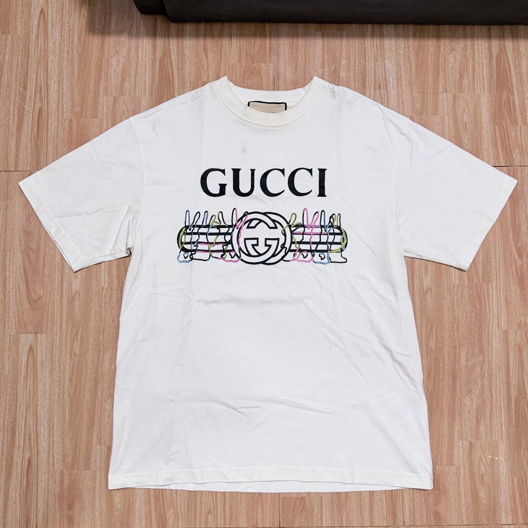 Gucci White Interlocking G Print T-Shirt (Category: Shirts) located in Butuan. Submitted by nielben13 (Listing ID 1468411469, Image 1). Description: - Authentic Gucci graphic tee in clean white cotton - Classic crew neck and short sleeves with a comfortable regular fit - Features bold black Gucci lettering with colorful interlocking G and striped artwork - Interior woven neck tag and care labels completely intact - Ideal everyday piece to elevate