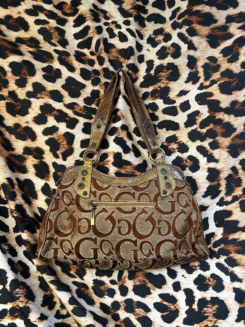 Guess Brown Monogram Shoulder Bag Y2K Snake Print (Category: Shoulder Bags) located in Los Banos. Submitted by samsukehiro (Listing ID 1468382979, Image 2). Description: Guess shoulder bag in brown monogram fabric. Snake print panels, metal grommets, and large gold-tone G logo buckle on the front. Double straps, outer zip pocket. Inside lining is tearing near the zipper closure. Wear and fraying around the seams and fabric edges..