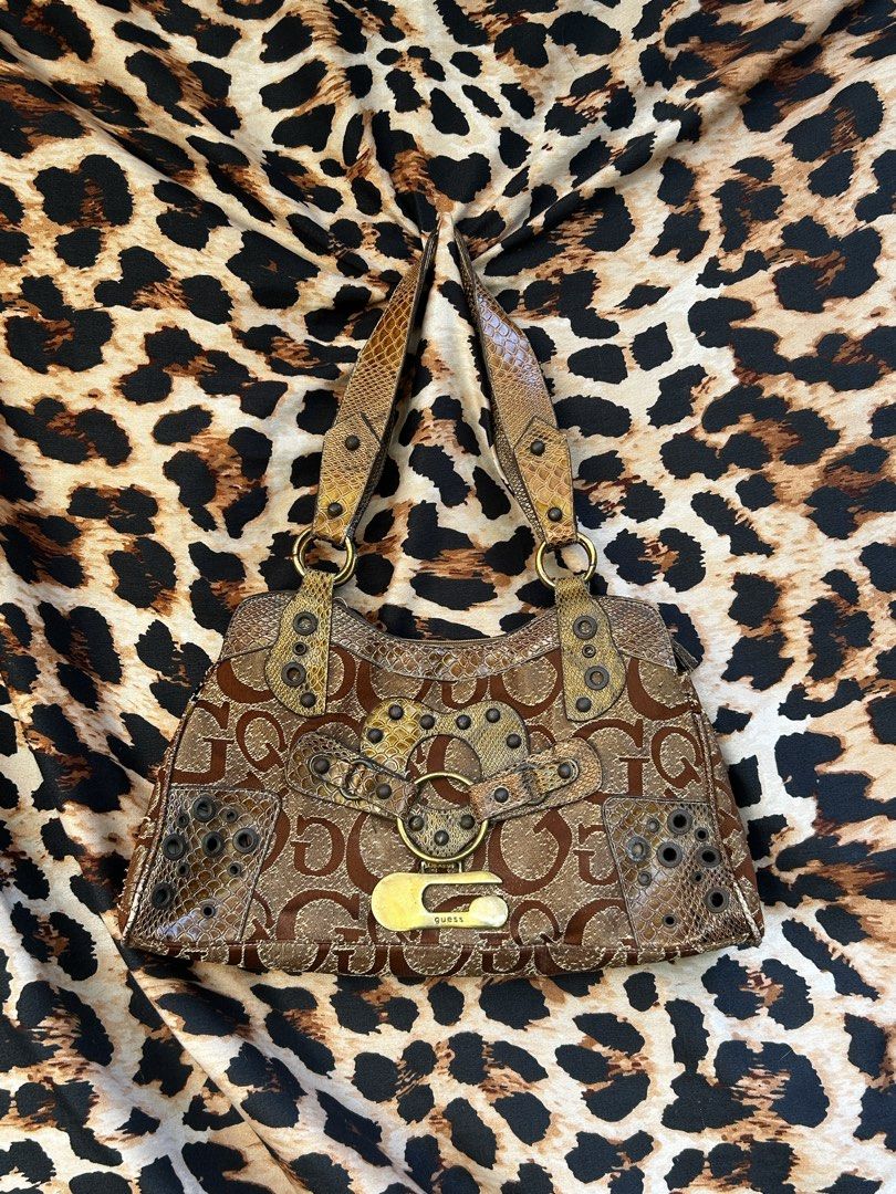 Guess Brown Monogram Shoulder Bag Y2K Snake Print (Category: Shoulder Bags) located in Los Banos. Submitted by samsukehiro (Listing ID 1468382979, Image 1). Description: Guess shoulder bag in brown monogram fabric. Snake print panels, metal grommets, and large gold-tone G logo buckle on the front. Double straps, outer zip pocket. Inside lining is tearing near the zipper closure. Wear and fraying around the seams and fabric edges..