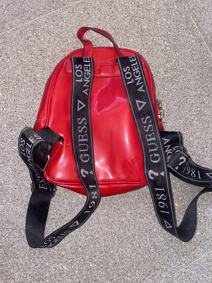 Guess Los Angeles Red Patent Mini Backpack (Category: Backpacks) located in Pasay City. Submitted by violetttttttttttttt (Listing ID 1468358289, Image 2). Description: - Brand: Guess - Style: Mini backpack in glossy red patent material with chic chevron quilting and embossed triangle logo - Straps: Black webbed shoulder straps with iconic white 'Guess Los Angeles 1981' lettering - Hardware: Premium gold-tone hardware with dual zipper pulls - Inte