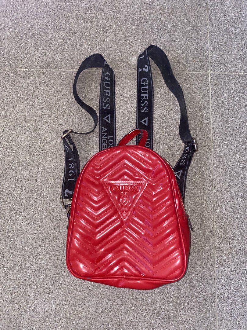 Guess Los Angeles Red Patent Mini Backpack (Category: Backpacks) located in Pasay City. Submitted by violetttttttttttttt (Listing ID 1468358289, Image 1). Description: - Brand: Guess - Style: Mini backpack in glossy red patent material with chic chevron quilting and embossed triangle logo - Straps: Black webbed shoulder straps with iconic white 'Guess Los Angeles 1981' lettering - Hardware: Premium gold-tone hardware with dual zipper pulls - Inte
