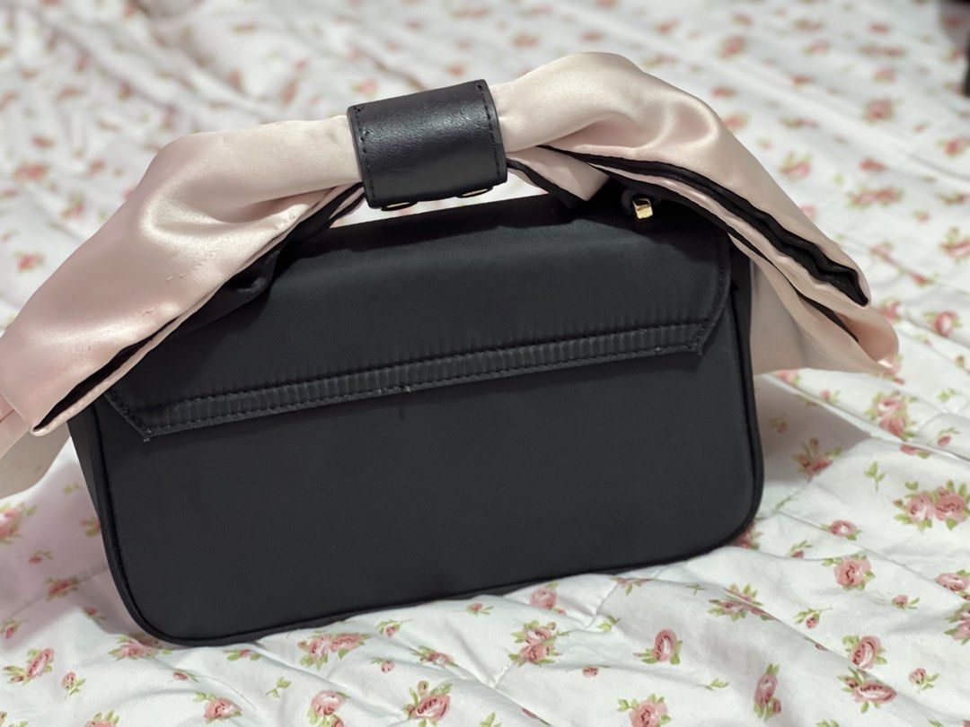 Hello Kitty Black hand Bag with Satin Bow Handle (sling strap missing) (Category: Shoulder Bags) located in Pasig City. Submitted by morilove (Listing ID 1468304827, Image 2). Description: - Brand: Kitty - Color: Black with a pink and black satin bow - Material: Structured design with fabric lining - Hardware: Gold metal logo lettering on front flap - Closure: Secure magnetic snap - Interior: Includes a woven Kitty label patch inside the pocket -