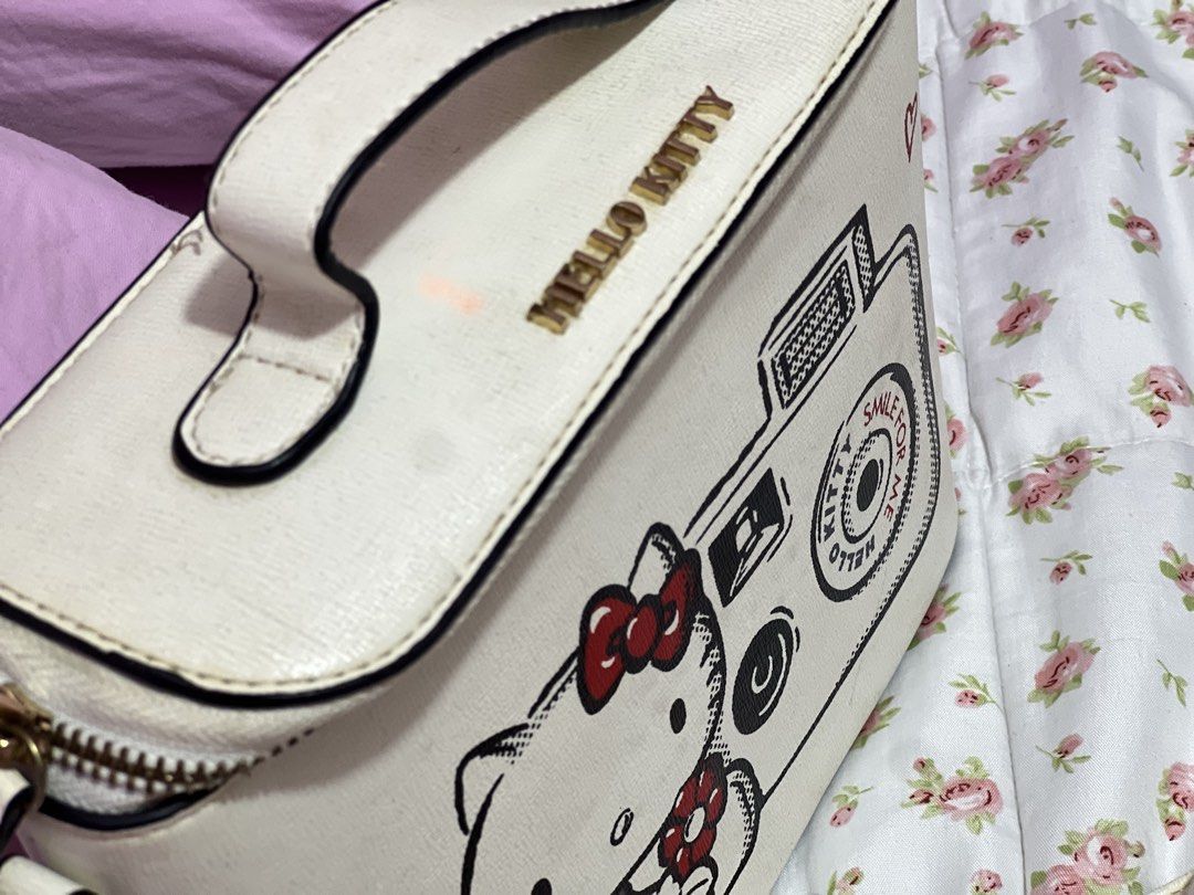 Hello Kitty Camera Design Crossbody Bag (Category: Cross-body Bags) located in Pasig City. Submitted by morilove (Listing ID 1468299892, Image 3). Description: - Authentic Sanrio Kitty vanity box bag - Features adorable camera graphic with striking red accents - Elegant gold-tone hardware and secure zipper closure - Includes a matching adjustable and detachable shoulder strap - Practical interior with black fabric lining and convenient slip pocke
