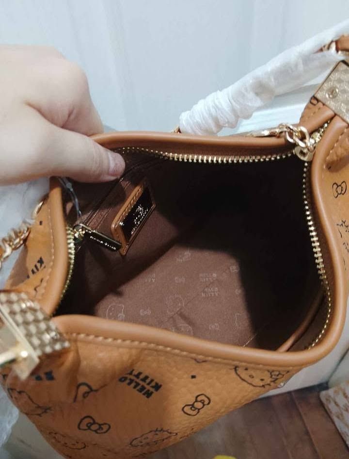 Hello Kitty Monogram Tan Shoulder Bag with Chain Strap (Category: Shoulder Bags) located in Manila. Submitted by hisandherscloset2025 (Listing ID 1468461859, Image 2). Description: - Authentic Kitty shoulder bag in a stylish tan colorway - Includes a chic gold chain handle for hand or shoulder wear - Comes with an extra sling strap (still wrapped in protective plastic) - Interior features branded fabric lining and a secure zippered pocket - Compl