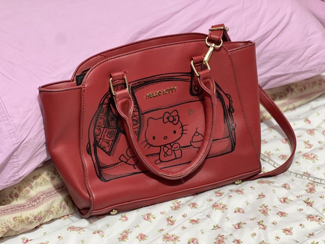 Hello Kitty Red Satchel Shoulder Bag (Category: Shoulder Bags) located in Pasig City. Submitted by morilove (Listing ID 1468298082, Image 1). Description: - Material: Red faux leather with Kitty front graphic - Hardware: Gold-tone - Closure: Zipper closure with top handles - Strap: Includes matching adjustable shoulder strap - Dimensions: Approx. 13 inches across x 10 inches tall - Interior: Clean black fabric lining with organizational pockets -