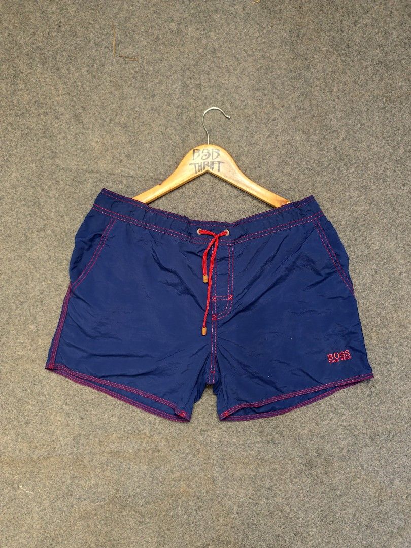 Hugo Boss Swim Shorts (Category: Swim Trunks & Board Shorts) located in Cordova. Submitted by bsb.streetluxvintage.clothing (Listing ID 1468424552, Image 2). Description: - Brand: Hugo Boss - Color: Blue with striking red contrast stitching and matching red drawstring - Features: Back pocket with flap closure and red tab, embroidered Hugo Boss logo near the hem - Material: Lightweight, quick-dry fabric ideal for swimming and beachwear.