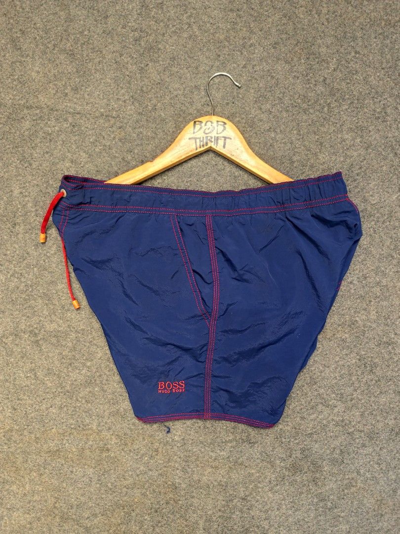Hugo Boss Swim Shorts (Category: Swim Trunks & Board Shorts) located in Cordova. Submitted by bsb.streetluxvintage.clothing (Listing ID 1468424552, Image 1). Description: - Brand: Hugo Boss - Color: Blue with striking red contrast stitching and matching red drawstring - Features: Back pocket with flap closure and red tab, embroidered Hugo Boss logo near the hem - Material: Lightweight, quick-dry fabric ideal for swimming and beachwear.