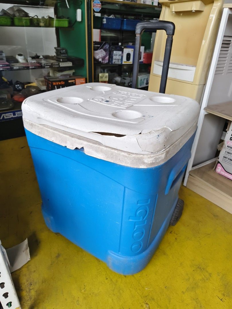 Igloo Ice Cube Rolling Cooler Blue White (Category: Food Organization & Storage) located in Pasig City. Submitted by maming73 (Listing ID 1468306365, Image 2). Description: - Color: Blue and White - Portable design: Telescoping handle and smooth-rolling wheels - Convenience: 4 molded cup holders on the lid - Condition: Fully functional handle and wheels; noticeable scuffs on the body and cracks around the lid edges - Perfect for beach trips, outi