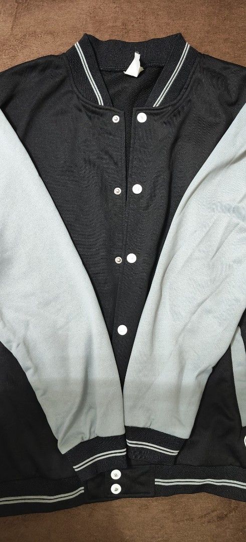 INSPI Varsity Jacket Black and Grey Size XL (Category: Coats, Jackets and Outerwear) located in Manila. Submitted by snz_shop (Listing ID 1468460195, Image 2). Description: - Brand: INSPI - Style: Varsity Jacket - Size: XL - Color: Black body with grey sleeves - Closure: Snap button - Features: Ribbed collar, cuffs, and hem with white striping, plus front welt pockets - Condition: Clean fabric overall with clear brand tag attached inside neckline