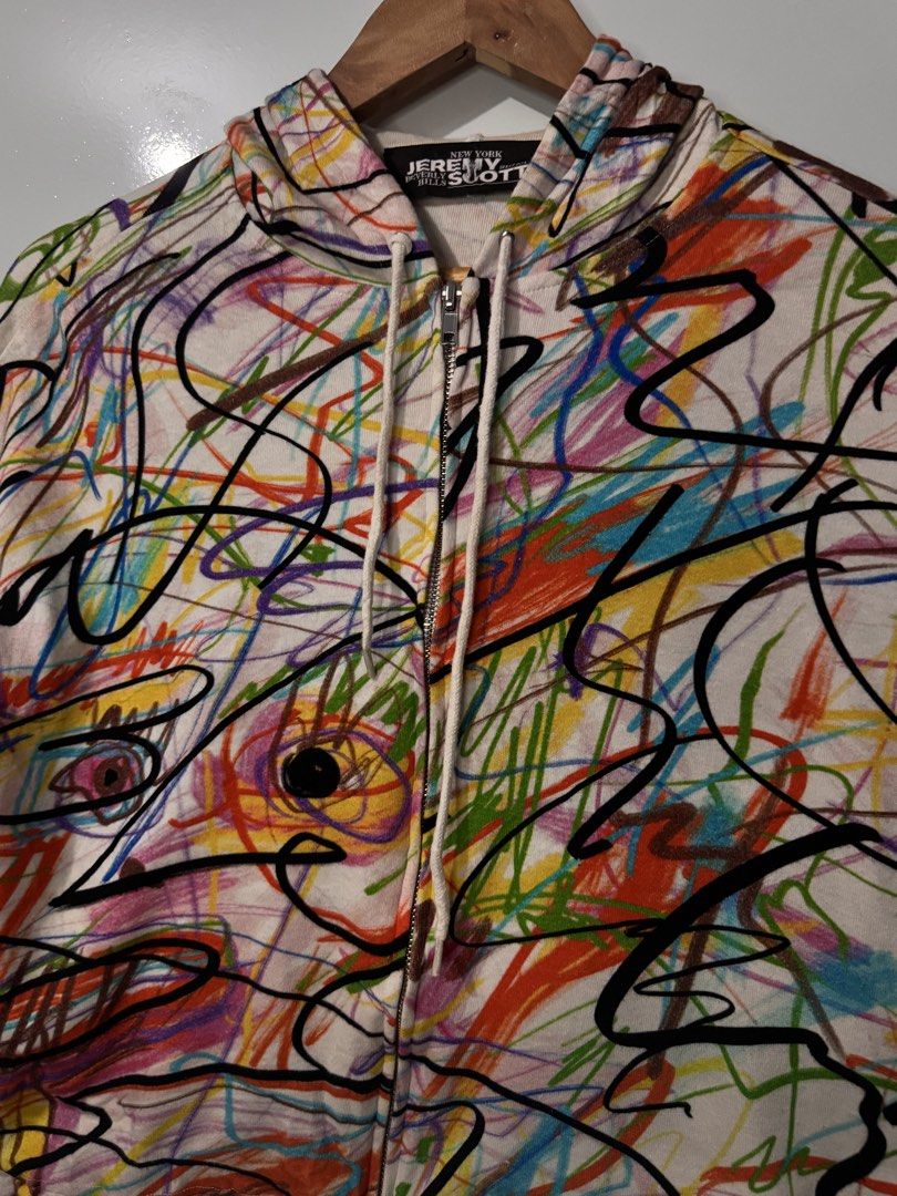 Jeremy Scott Scribble Print Zip Up Hoodie (Category: Coats, Jackets and Outerwear) located in Alaminos. Submitted by outfitcheck.ph (Listing ID 1468396023, Image 2). Description: - Brand/Designer: Jeremy Scott - Design: All-over multicolor abstract scribble and crayon doodle print on a clean white base - Features: Zip-up closure, drawstring hood, and adjustable drawstring hem for versatile styling - Vibe: Bold, playful, and artistic statement pie