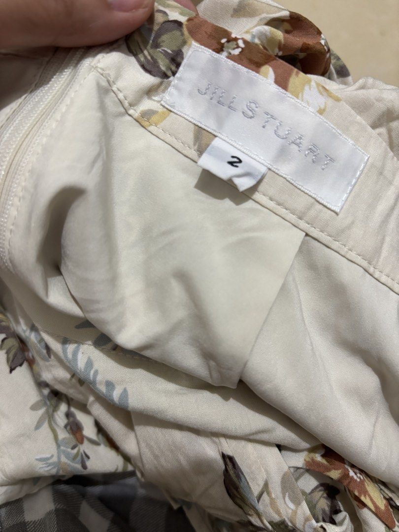 Jill Stuart Floral Long Skirt Size 2 (Category: Skirts) located in Manila. Submitted by van390867 (Listing ID 1468411078, Image 3). Description: - Brand: Jill Stuart Size 25 - Color/Pattern: Cream base with brown, green, and yellow floral print - Size: 2 (tag attached near waistband) - Closure: Side zipper - Details: Ruffled drape down the front, fully lined - Style: Cottagecore / vintage-inspired long skirt.