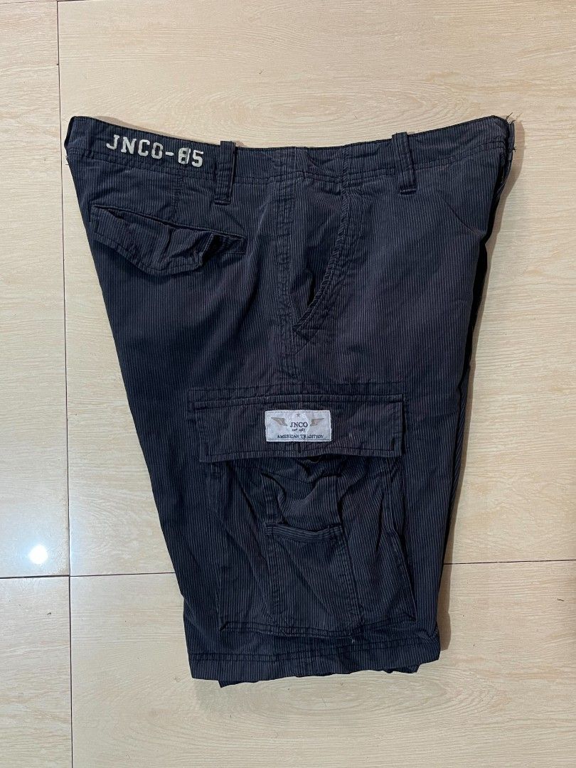 JNCO-85 Pinstripe Cargo Shorts Dark Grey (Category: Shorts) located in Manila. Submitted by kaloyyyyyy (Listing ID 1468346799, Image 3). Description: - Brand/Model: JNCO-85 dark grey pinstripe cargo shorts - Style: Classic Y2K skater cargo - Storage: Multiple utility pockets including side cargo and rear button flaps - Details: Distinctive JNCO-85 back waistband embroidery, branded button closure, and fabric patch label - Material: Sturdy cotton 