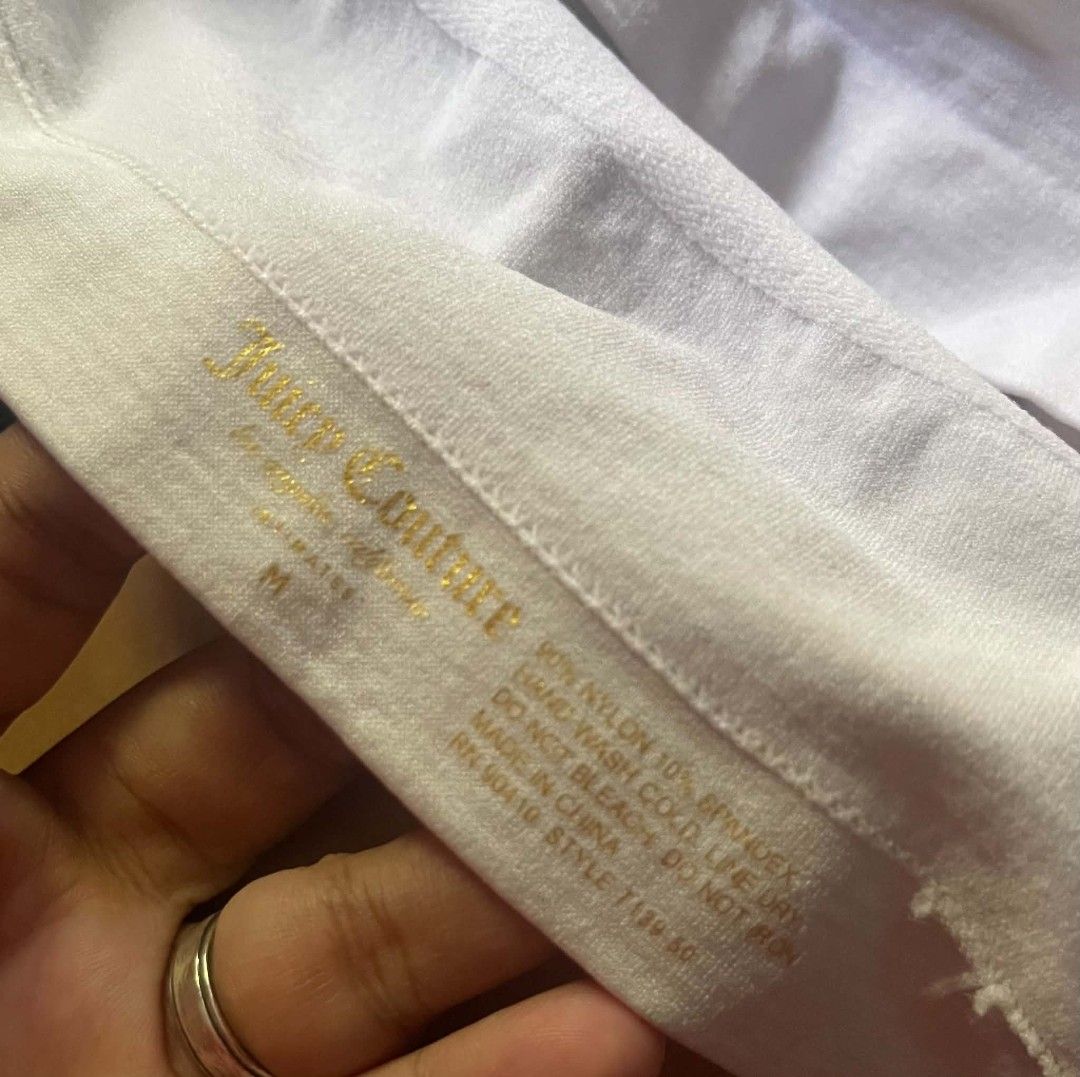 Juicy Couture White Cami Tank Top Size M (Category: Sleeveless) located in Gumaca. Submitted by makuliti (Listing ID 1468307628, Image 3). Description: - Brand: Juicy Couture - Size: M - Color: White with black straps - Material: 90% nylon, 10% spandex (super stretchy) - Design: Ribbed texture, V-neckline, seamless fitted body - Details: Black elastic straps featuring white Gothic script logo branding and gold stamped logo inside neckline - Condi