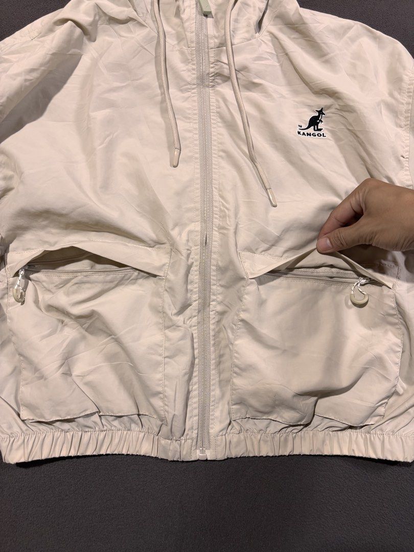 Kangol Beige Hooded Windbreaker Jacket (Category: Coats, Jackets and Outerwear) located in Mabalacat. Submitted by _limitlessfashion (Listing ID 1468300525, Image 2). Description: - Brand: Kangol Crop Windbreaker - Color: Beige - Size medium on tag - Length 21 - Width 24 - Crop vibe - No major issue, need wash only - Style: Lightweight cropped windbreaker - Features: Full zip front, adjustable drawstring hood, and elastic hem and cuffs - Pockets: