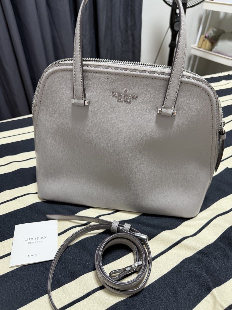 Kate Spade Patterson Dome Satchel Bag (Category: Tote Bags) located in Manila. Submitted by poreberqueeen (Listing ID 1468286187, Image 3). Description: Grey pebble leather satchel from Kate Spade New York. Structured dome shape with top zip closure and silver hardware. Includes dual top handles and a detachable shoulder strap. Interior has signature spade fabric lining, zippered pocket, and slip compartments. Protective metal feet on the bottom.