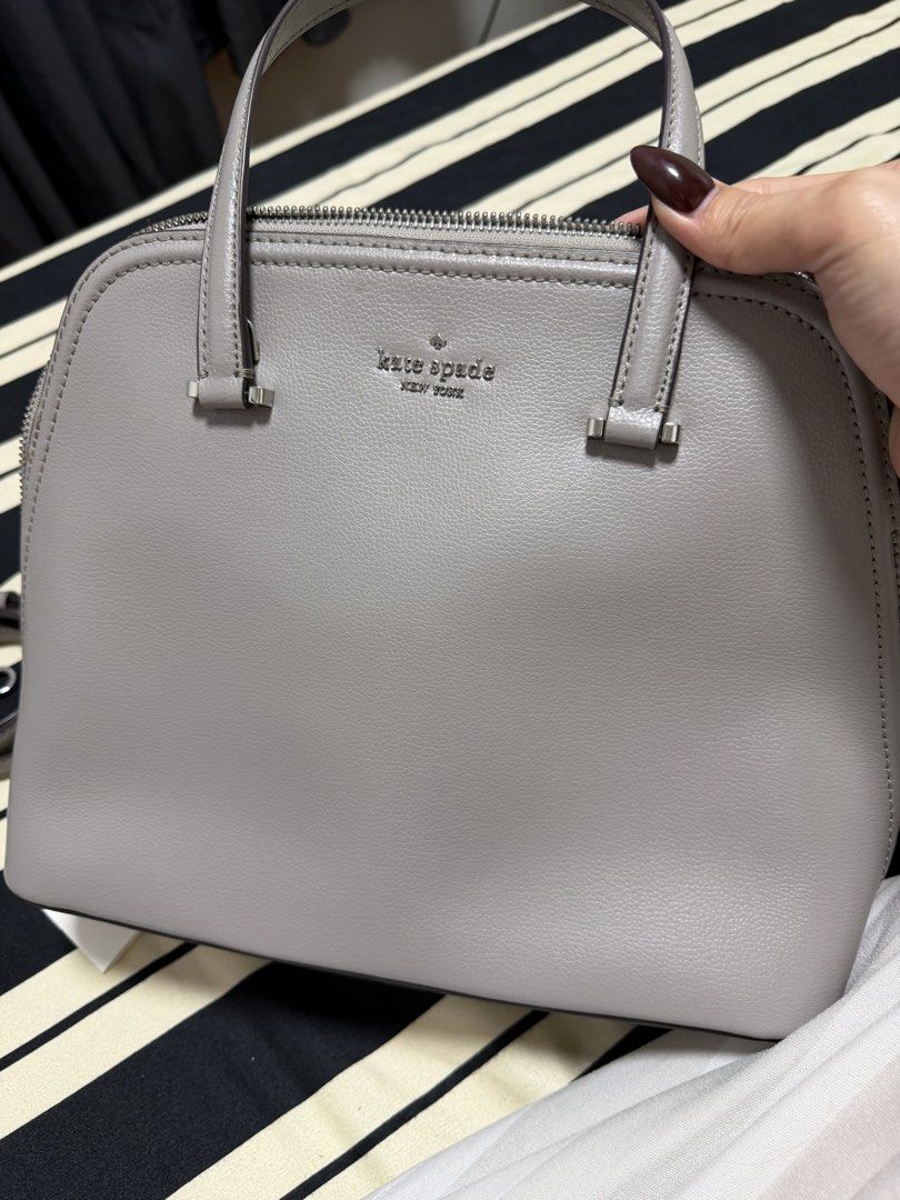 Kate Spade Patterson Dome Satchel Bag (Category: Tote Bags) located in Manila. Submitted by poreberqueeen (Listing ID 1468286187, Image 2). Description: Grey pebble leather satchel from Kate Spade New York. Structured dome shape with top zip closure and silver hardware. Includes dual top handles and a detachable shoulder strap. Interior has signature spade fabric lining, zippered pocket, and slip compartments. Protective metal feet on the bottom.
