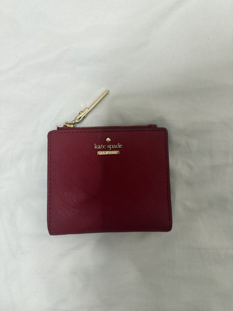 Kate Spade Red Leather Bifold Wallet (Category: Wallets & Card holders) located in Santa Rosa. Submitted by decluttering_. (Listing ID 1468499739, Image 1). Description: - Brand: Kate Spade - Color: Red with gold hardware and logo lettering - Lining: Chic black and white stripe lining - Exterior: Back ID window - Interior: Card slots and note compartment - Pocket: Zip coin pocket along the top.