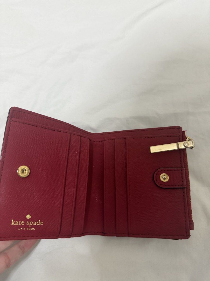 Kate Spade Red Leather Bifold Wallet (Category: Wallets & Card holders) located in Santa Rosa. Submitted by decluttering_. (Listing ID 1468499739, Image 3). Description: - Brand: Kate Spade - Color: Red with gold hardware and logo lettering - Lining: Chic black and white stripe lining - Exterior: Back ID window - Interior: Card slots and note compartment - Pocket: Zip coin pocket along the top.