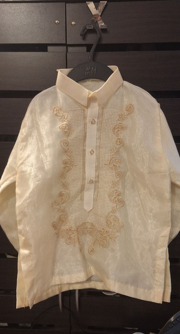 KIDS Barong Tagalog (Category: Babies & Kids Fashion) located in General Trias. Submitted by aeunice (Listing ID 1468352599, Image 1). Description: Size: 10 (8 to 10yrs) Cream traditional Filipino barong with long sleeves and gold embroidery. Slightly tear unnoticed by the right arm. Lightweight, sheer formal wear featuring transparent buttons. Perfect for weddings and formal events. Meet up / Shipping via Lalamove, JnT, Gogo Express & LBC .