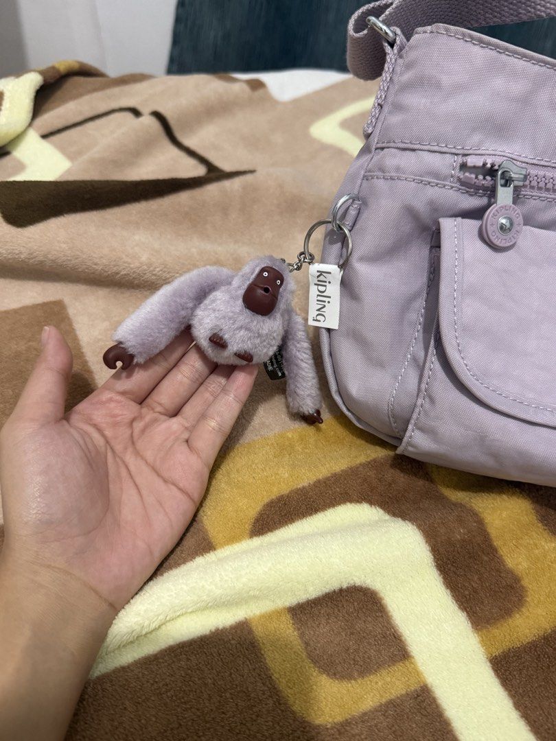 Kipling Crossbody Bag with Sadie Monkey Keychain (Category: Cross-body Bags) located in Manila. Submitted by lianerose123 (Listing ID 1468307508, Image 2). Description: - Brand: Kipling Once lang nagamit, kabibili lang last month - Color: Light purple - Style: Shoulder bag with adjustable strap - Pockets: Front flap pocket, top zipper compartment, and multiple compartments for easy organization - Details: Iconic round Kipling logo patch - Inclusi
