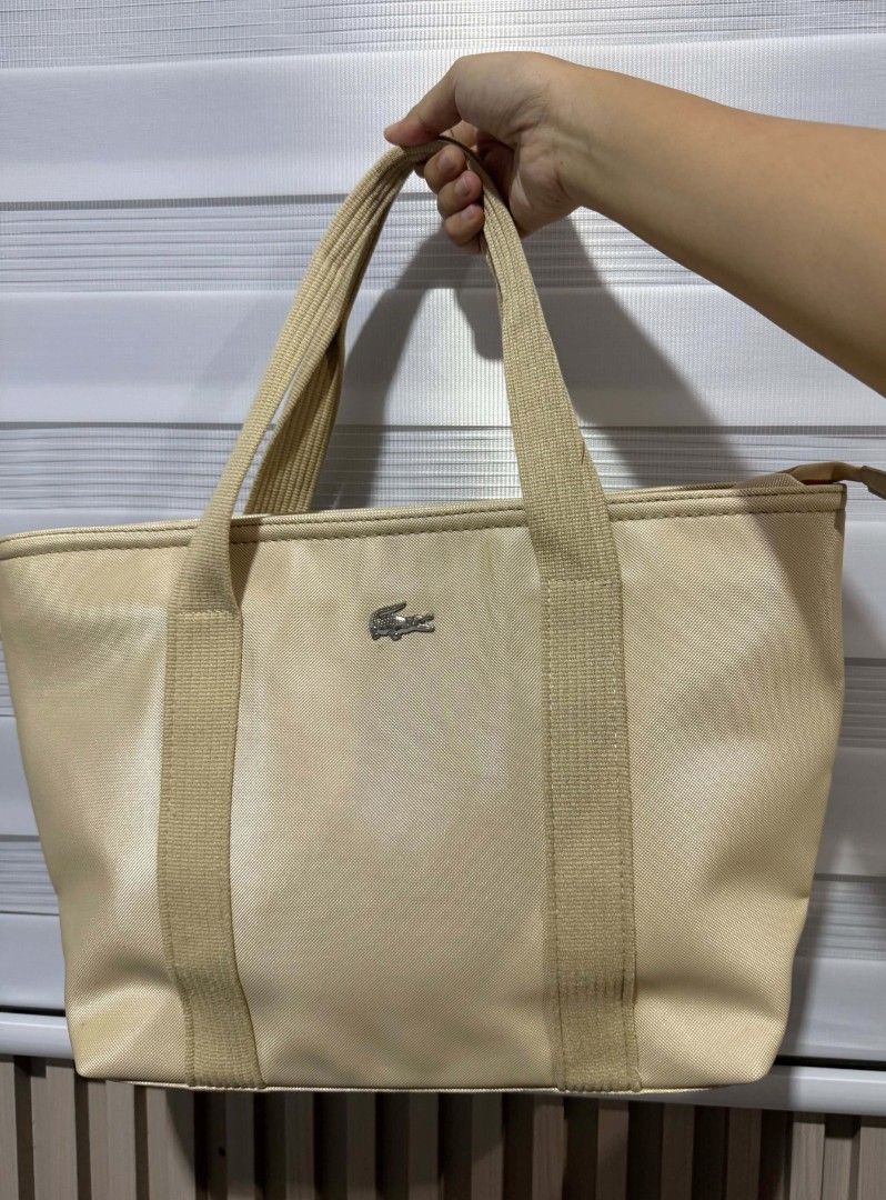 Lacoste Beige Tote Bag (Category: Tote Bags) located in Iloilo. Submitted by frdhbrd (Listing ID 1468387577, Image 1). Description: - Brand: Lacoste - Color: Versatile beige - Material: Durable woven fabric with structured handles - Closure: Secure zippered top - Interior: Clean fabric lining with zippered and slip pockets for easy organization - Condition: Excellent, clean interior - Style: Minimalist everyday carryall NOT FROM UKAY.