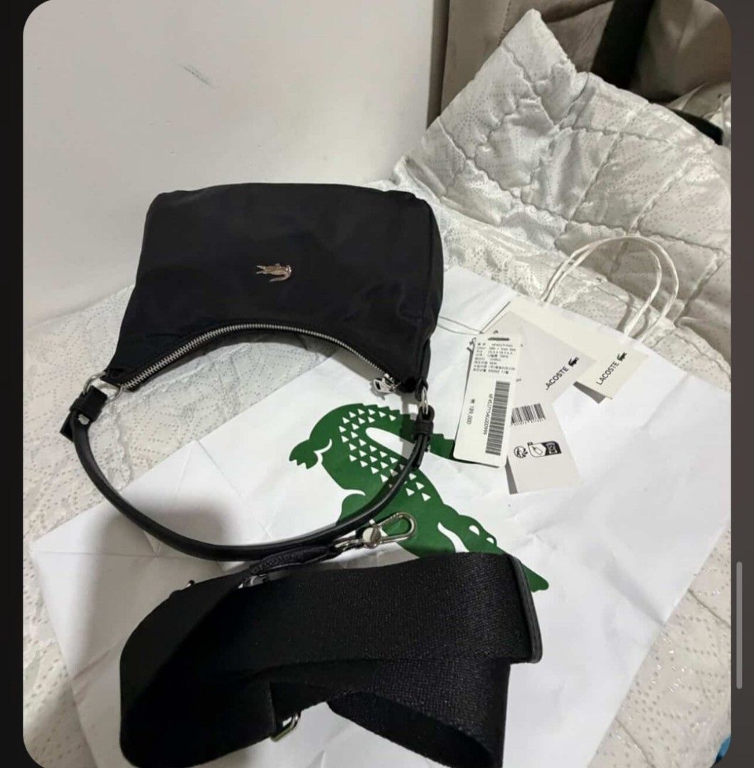 Lacoste Black Nylon Shoulder Bag (Category: Shoulder Bags) located in Polomolok. Submitted by legadad94559 (Listing ID 1468409675, Image 3). Description: - Brand: Lacoste - Color: Classic Black - Material: Lightweight durable nylon with sleek silver hardware - Hardware/Logo: Signature metal crocodile logo on the front - Closure: Secure top zip closure - Straps: Includes a short carry handle and a detachable fabric strap for versatile styling - Co