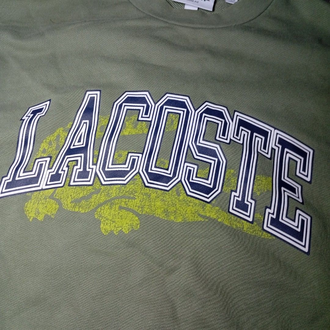 Lacoste Olive Green Collegiate Logo Sweatshirt (Category: Coats, Jackets and Outerwear) located in Davao. Submitted by tj-289a (Listing ID 1468379900, Image 2). Description: - Authentic olive green Lacoste sweatshirt in a comfortable loose fit - Heavyweight premium cotton material - Large collegiate chest lettering with a stylish faded crocodile graphic - Signature small embroidered green crocodile logo patch near the sleeve cuff - Classic crew n