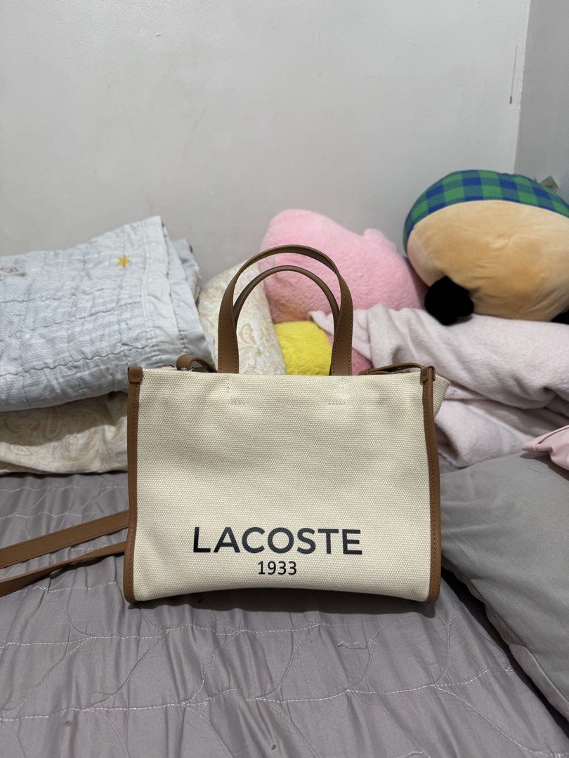 Lacoste Small Heritage Canvas Tote (Category: Tote Bags) located in Makati City. Submitted by annelouisec (Listing ID 1468435704, Image 2). Description: Description: Dimensions: 27cm x 21cm x 12.5cm / 10.6” x 8.3” x 4.9” Cotton outer Zip closure on top Adjustable strap: 107cm / 42” 1 zipped inside pocket Outside: Cotton (100%) SRP Bought: June 2026 Can provide invoice for payment proof. RFS: Selling because I rarely use it anymore :) .