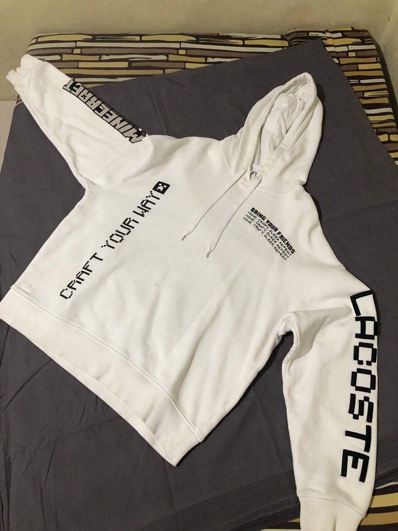 Lacoste x Minecraft White Hoodie (Category: Coats, Jackets and Outerwear) located in Cavite. Submitted by mayinyerg (Listing ID 1468380277, Image 1). Description: - Brand: Lacoste x Minecraft - Color: White - Fit: Regular fit, heavyweight fabric - Design: Graphic prints on front, back, and sleeves with embroidered crocodile logo near the hem - Features: Drawstring hood, ribbed cuffs and hem - Condition: Noticeable rust-colored stains on the left 