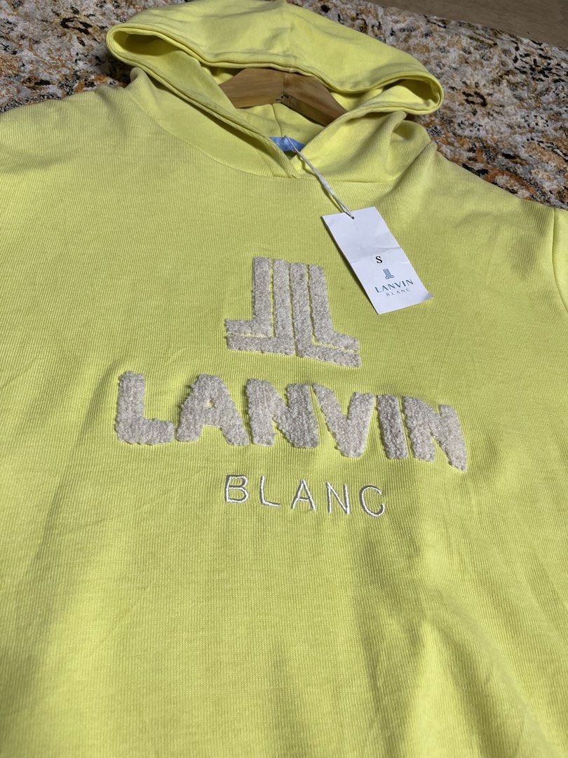 Lanvin Blanc Yellow Hoodie Size S (Category: Hoodies) located in Caloocan City. Submitted by flipthatcloths8600 (Listing ID 1468416098, Image 2). Description: - Brand: Lanvin Blanc - Color: Bright yellow with white fuzzy logo embroidery and contrast tan hem - Size: S (tag attached) - Condition: Brand new, unworn, pristine fabric - Inclusions: Original store tags still on string - Features: Adjustable hood, long sleeves, and ribbed cuffs.