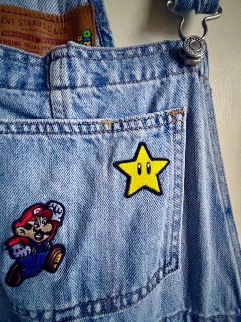 Levi's x Super Mario Denim Overalls Size XS (Category: Coats, Jackets and Outerwear) located in Manila. Submitted by erin_closet (Listing ID 1468308886, Image 3). Description: - Brand: Levi's x Super Mario Collaboration - Style: Denim overall shorts - Wash/Color: Light wash blue - Size: XS - Details: Embroidered Mario, Super Star, Mushroom, Fire Flower, and coin patches; adjustable shoulder straps with metal hardware - Back Details: Levi's brande