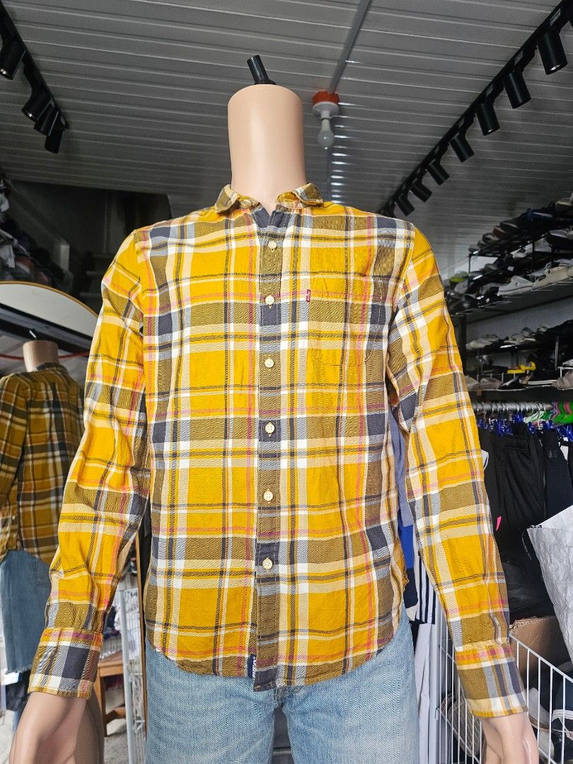 Levi's yellow and grey plaid checked long-sleeve (Category: Formal Shirts) located in Baguio. Submitted by kayeonlineshop (Listing ID 1468298031, Image 2). Description: long-sleeve button-up plaid shirt featuring a bold mustard yellow and dark grey/black checked pattern accented with thin white and red lines. It has a classic casual collar, a single buttoned chest pocket with the iconic red Levi's logo tab, and a regular fit structure..