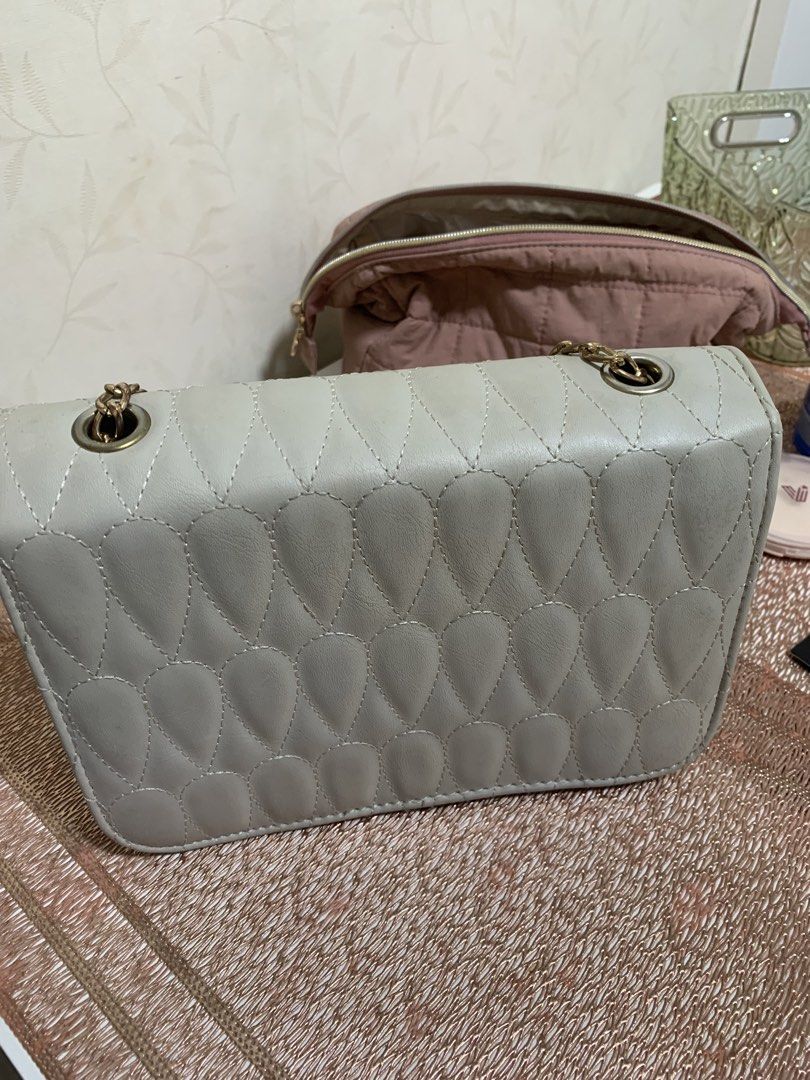 Light Grey Quilted Shoulder Bag with Gold Chain (Category: Luxury Bags & Wallets) located in Makati City. Submitted by FashionFactory (Listing ID 1468369951, Image 3). Description: - Color: Light grey - Pattern: Unique teardrop quilted design - Hardware & Strap: Gold chain strap with matching clover turn-lock clasp - Interior: Dark fabric lining with a secure zipper pocket (very clean) - Condition: Shows light daily wear on the exterior leather a