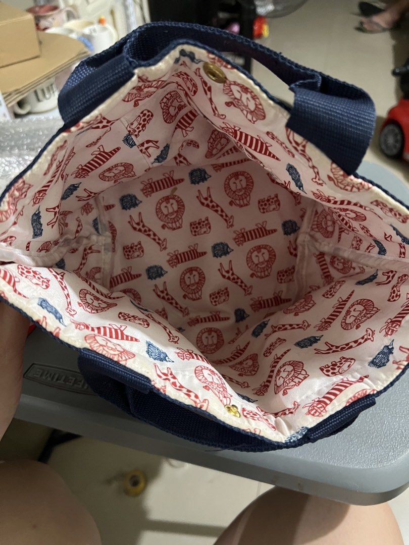 Lisa Larson Red Hedgehog Tote Bag (Category: Tote Bags) located in Manila. Submitted by ajdfinds (Listing ID 1468380104, Image 2). Description: - Red faux leather tote bag with adorable black hedgehog graphic - Contrast blue handles and secure snap button closure - Features playful Lisa Larson animal print lining (lions, giraffes, hedgehogs) - Includes official Lisa Larson fabric tag inside - Compact size, ideal as a stylish lunch bag or small ev