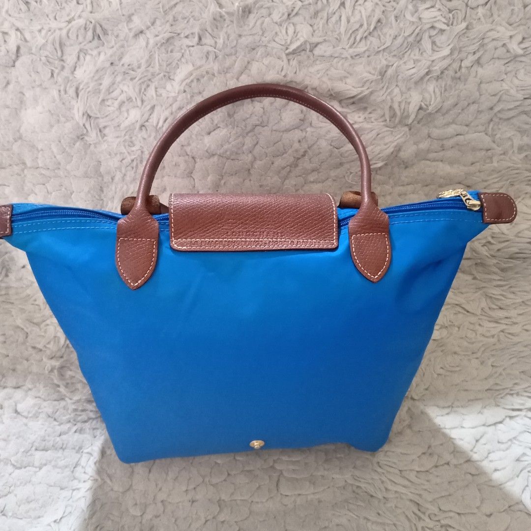 Longchamp Le Pliage Blue Tote Bag (Category: Luxury Bags & Wallets) located in Baguio. Submitted by sheren_signatures (Listing ID 1468287287, Image 2). Description: - Brand: Longchamp - Style: Shoulder tote bag (Medium/Large with long handles) - Material: Bright blue nylon body with brown leather handles and flap - Hardware: Elegant gold-tone on zipper pull and snap button - Interior: White lining with a small open slip pocket and official brand 