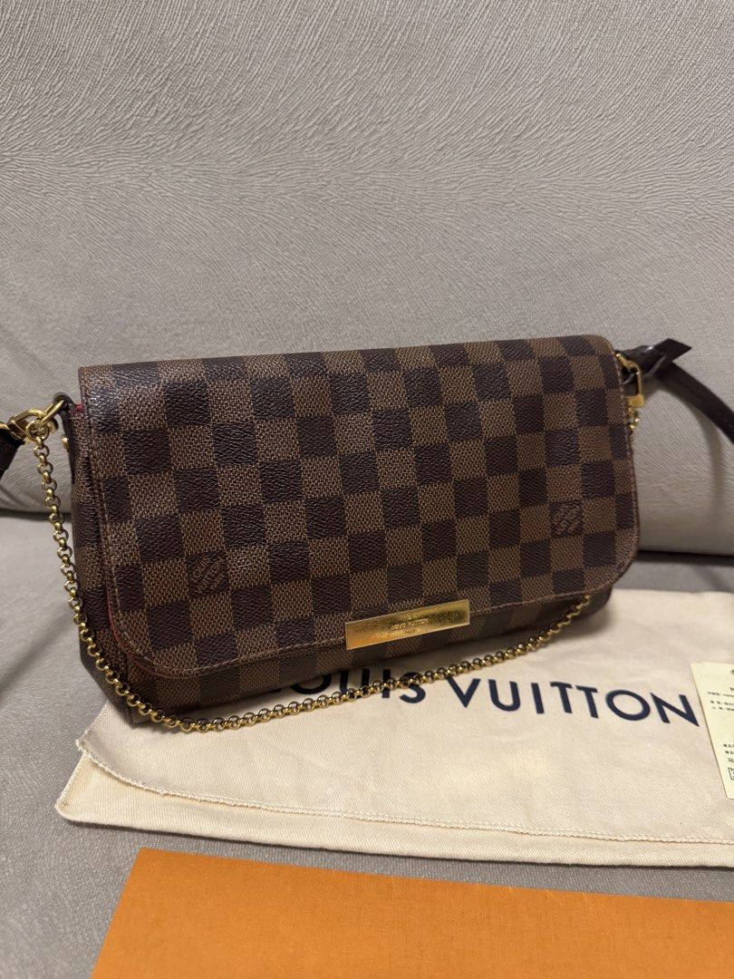 Louis Vuitton favorite (Category: Luxury Bags & Wallets) located in Taguig. Submitted by byebyebabies (Listing ID 1468302735, Image 1). Description: - Brand: Louis Vuitton - Material: Iconic Damier Ebene canvas with brown leather shoulder strap - Hardware: Elegant gold-tone chain strap and front plaque - Interior: Vibrant red lining inside the flap - Inclusions: Original cream dust bag and orange paper envelope - Condition: Excellent, well-mainta