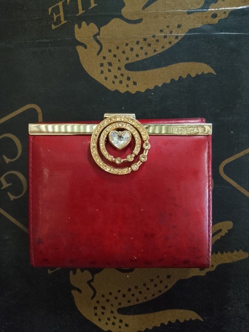 Lovcat Red Leather Tri-fold Wallet with Rhinestone Clasp (Category: Wallets & Card holders) located in Manila. Submitted by amiarnajea96023 (Listing ID 1468327846, Image 1). Description: - Brand/Model: Authentic Lovcat Paris tri-fold wallet - Color & Material: Vibrant red leather with gold-tone hardware - Special Details: Eye-catching rhinestone circle clasp with a center heart detail - Interior Layout: Multiple card slots, clear ID window, and s