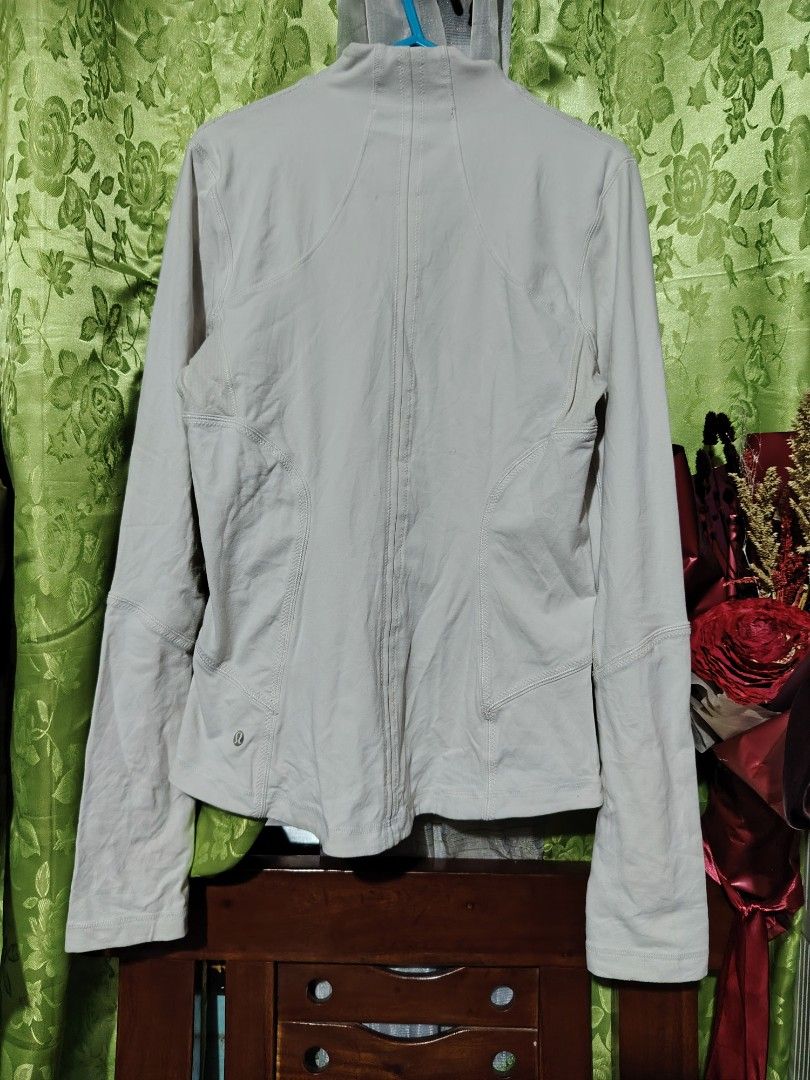 Lululemon White Zip Up Jacket (Category: Coats, Jackets and Outerwear) located in Santa Rosa. Submitted by RRRR0520 (Listing ID 1468334225, Image 2). Description: - Brand: Lululemon - Color: White - Style: Full zip athletic jacket with high collar - Features: Thumbholes on sleeves, secure zippered front pockets, branded zipper pull, and subtle logo near the back hem - Flaw/Note: Has custom embroidered 'DRILLING INC' text near the bottom front hem