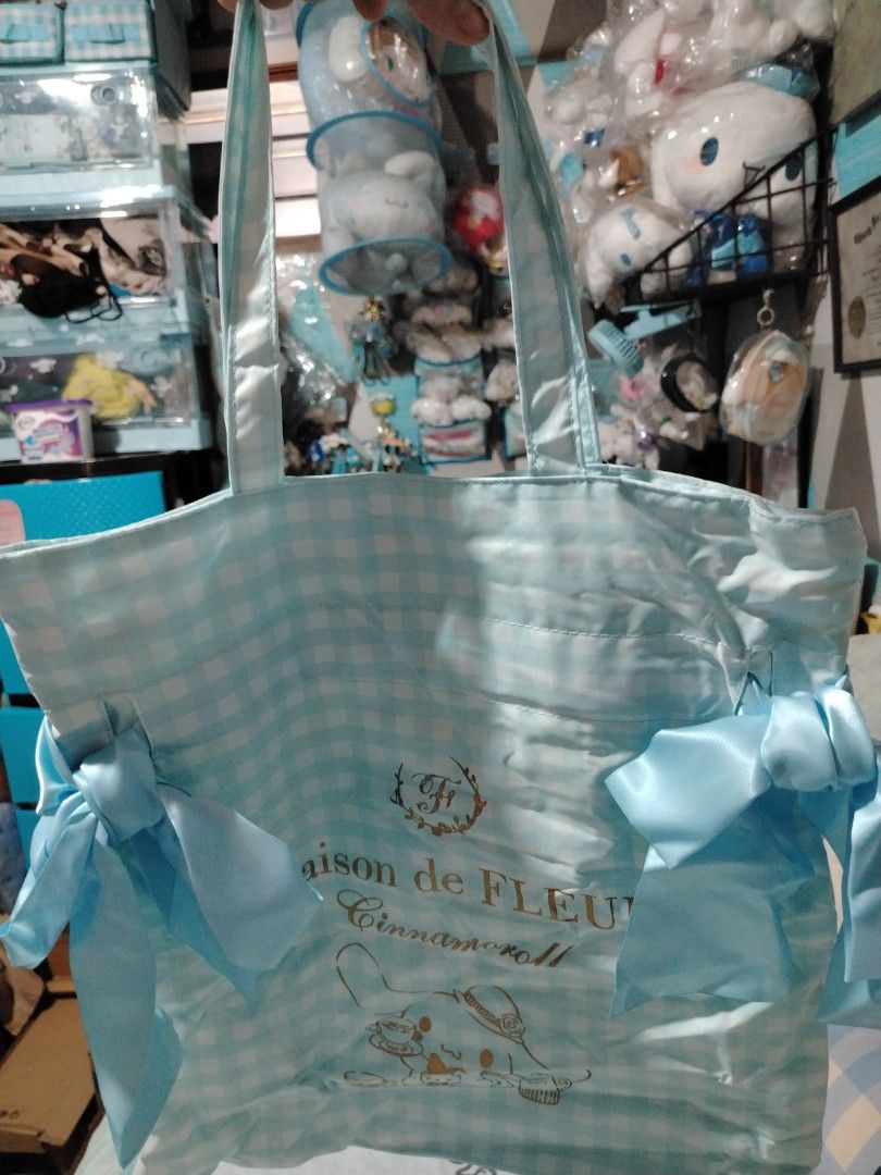 Maison de FLEUR Cinnamoroll Light Blue Gingham Tote Bag (Category: Tote Bags) located in Manila. Submitted by joycechua439850 (Listing ID 1468306339, Image 1). Description: - Authentic Maison de FLEUR x Sanrio collaboration - Light blue and white all-over gingham print - Large gold foil graphic of Cinnamoroll having tea with a teddy bear - Cute matching blue satin ribbons on both side panels - Comfortable double shoulder handles - Brand new with 